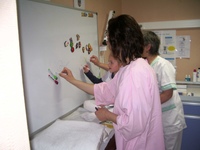 Une enfant et les infirmières dessinent ensemble au feutre sur le tableau blanc