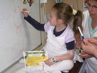 Une enfant hospitalisée dessine sur le tableau blanc magnétique