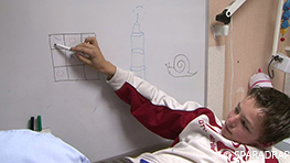 En pédiatrie, un adolescent fait un jeu de morpion sur un tableau effaçable à sec avant une prise de sang.
