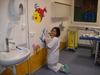 Une infirmière décore la salle de soins en peignant un mur
