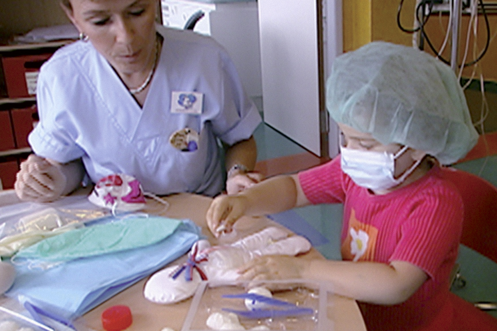 Une petite fille joue au docteur sur une poupée auprès d'une infirmière