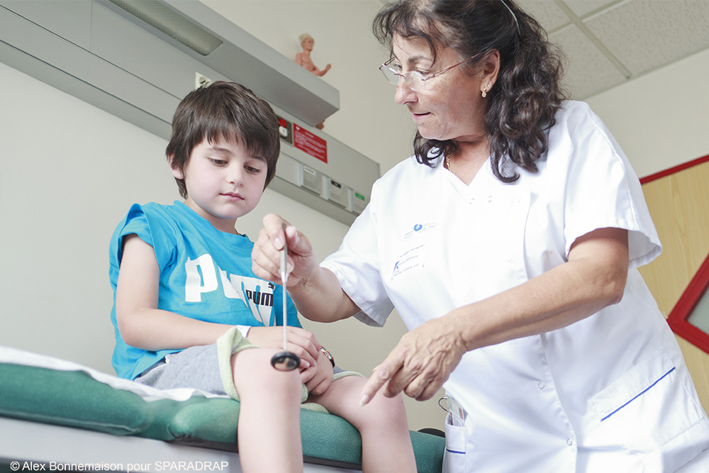 Une médecin réalise un test des réflexes sur un enfant