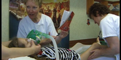 une infirmière lit un livre à un enfant pendant qu'il reçoit des soins